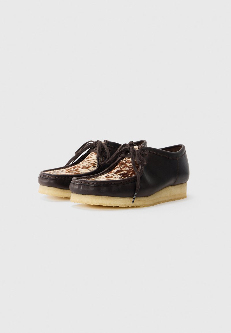 Chaussures en cuir brun avec une tige en tissu à motif, bout rond et lacets. Elles sont dotées d'une semelle en caoutchouc de couleur claire.