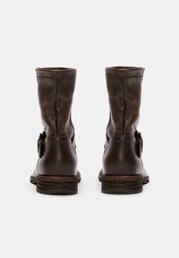 Bottes basses en cuir marron à texture lisse, avec une boucle latérale, un talon empilé et un design simple et classique.