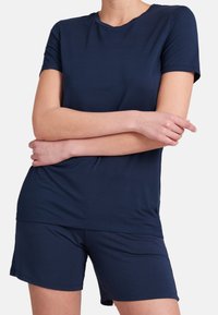 Marinblå t-shirt med kort ärm som matchas med korta byxor; mjukt, lättviktigt tyg med en slät textur och klassisk rundhalsringning.