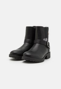 Černé kožené kotníkové boty s hladkou texturou, vybavené páskem a stříbrným srdcovým detailem. Plná podrážka a zaoblený špičkový design.