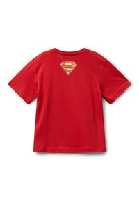 Červené tričko s krátkým rukávem s malým žlutým a červeným logem Supermana na horní části zad, uložené na bílém pozadí.