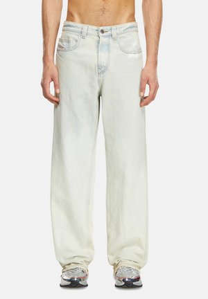 Jeans en denim délavé avec une coupe décontractée, présentant des jambes droites, des coutures contrastées et un design à cinq poches.