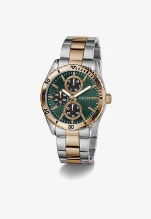 Orologio da polso in metallo bicolore argento e oro con quadrante verde, tre quadranti neri secondari, indici delle ore dorati e logo GUESS sul lato destro.