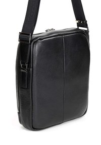 Borsa a tracolla in pelle nera con superficie crestata, forma quadrata, chiusura superiore a zip e tracolla regolabile. Tasca laterale con zip.