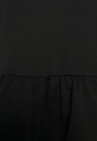 Svart plagg med en mjuk och slät textur samt en volangkant, som har en enkel design och enhetlig färg genom hela.