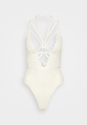 Body en dentelle blanche avec un décolleté plongeant, des bretelles croisées, des motifs floraux complexes et un dos ouvert.