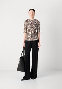 Leopard-print top with half sleeves, a structured neckline, paired with black wide-leg pants and a black tote bag. Smooth fabric texture.