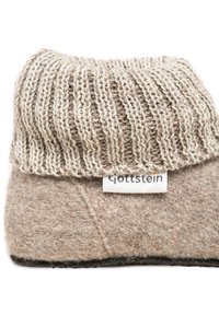 Pantofole di lana beige con ampio polsino lavorato a maglia e etichetta in tessuto "Gottstein" su sfondo bianco.
