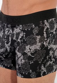 Černé trenýrky s květinovým a houndstooth vzorem. Elastický pas s logem značky, měkká textura a přiléhavý střih.
