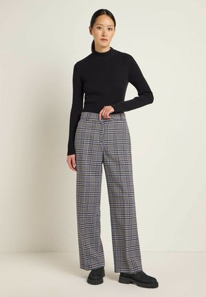 Black ribbed turtleneck top paired with wide-leg plaid trousers in blue, black, and beige tones; black platform shoes.