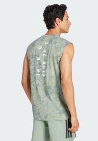 Bezramionkowy zielony top w stylu tie-dye z fakturowanym wykończeniem. Na plecach znajduje się biały napis "TRNG CLUB 24 7."