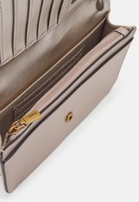 Portafoglio in finta pelle beige con finitura liscia, dotato di un compartimento con zip e chiusura a bottone automatico. Finiture in metallo color oro.