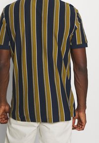 Kortärmad skjorta med vertikala ränder i marinblått, olivgrönt och vitt. Har en mjuk tygtextur och en klassisk passform.