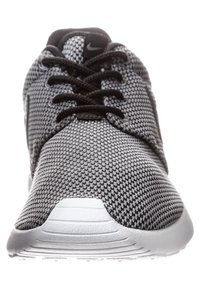 Black and gray mesh athletic shoe with a rounded toe, lace-up design, padded collar, and a white rubber sole featuring horizontal ridges.