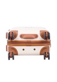 Hard-shell suitcase in cream with brown accents, featuring a textured surface, dual spinner wheels, and a top handle for easy carrying.