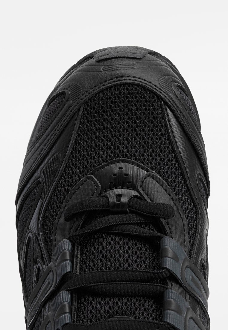 Zapatilla deportiva negra con materiales de malla y sintéticos, superficie texturizada, sistema de cordones integrado y lengüeta acolchada para mayor comodidad.