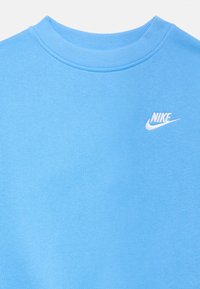 Jasnoniebieska bluza wykonana z bawełnianej tkaniny mieszanej, z prążkowanym okrągłym dekoltem i białym logo Nike wyhaftowanym na piersi.