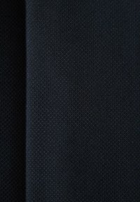 Rapea tummansininen kangas, jossa on hienovarainen kuvio, sileä viimeistely ja kevyt kiilto, taiteltu kerroksellisuuden näyttämiseksi.