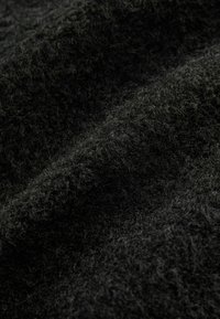 Gros plan d'un tissu en laine noire doux et texturé montrant des fibres fines et des plis délicats.