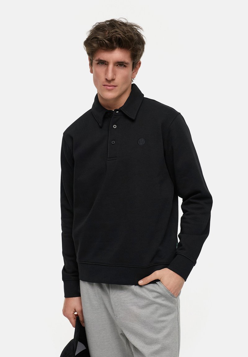 Schwarzer Pullover mit Kragen, drei Knöpfen und einem dezenten Logo auf der Brust. Weicher Stoff, lange Ärmel und gerippte Bündchen.