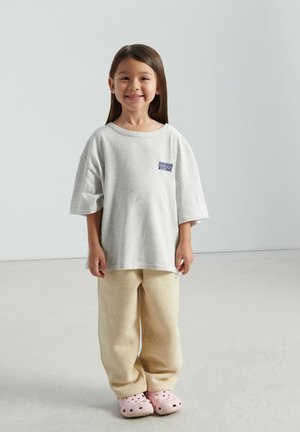 Gray oversized t-shirt with "American Vintage" logo, beige sweatpants, and pink clogs. Smooth fabric, relaxed fit, simple design.