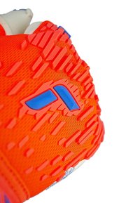 Chaussure de sport orange vif avec une semelle texturée et des accents bleus. Présente des motifs surélevés pour une adhérence et une tige en maille respirante.