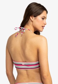 Randig bandeau-bikinitopp i rosa, blått och svart. Har ett halterneck-band i ryggen och textil med struktur. Enkel och färgglad design.