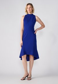 Blaustes, ärmelloses Kleid mit hohem Ausschnitt, figurbetontem Oberteil und ausgestellt geschnittenem Saum. Aus glattem Material gefertigt, mit dezenten Nahtdetails.