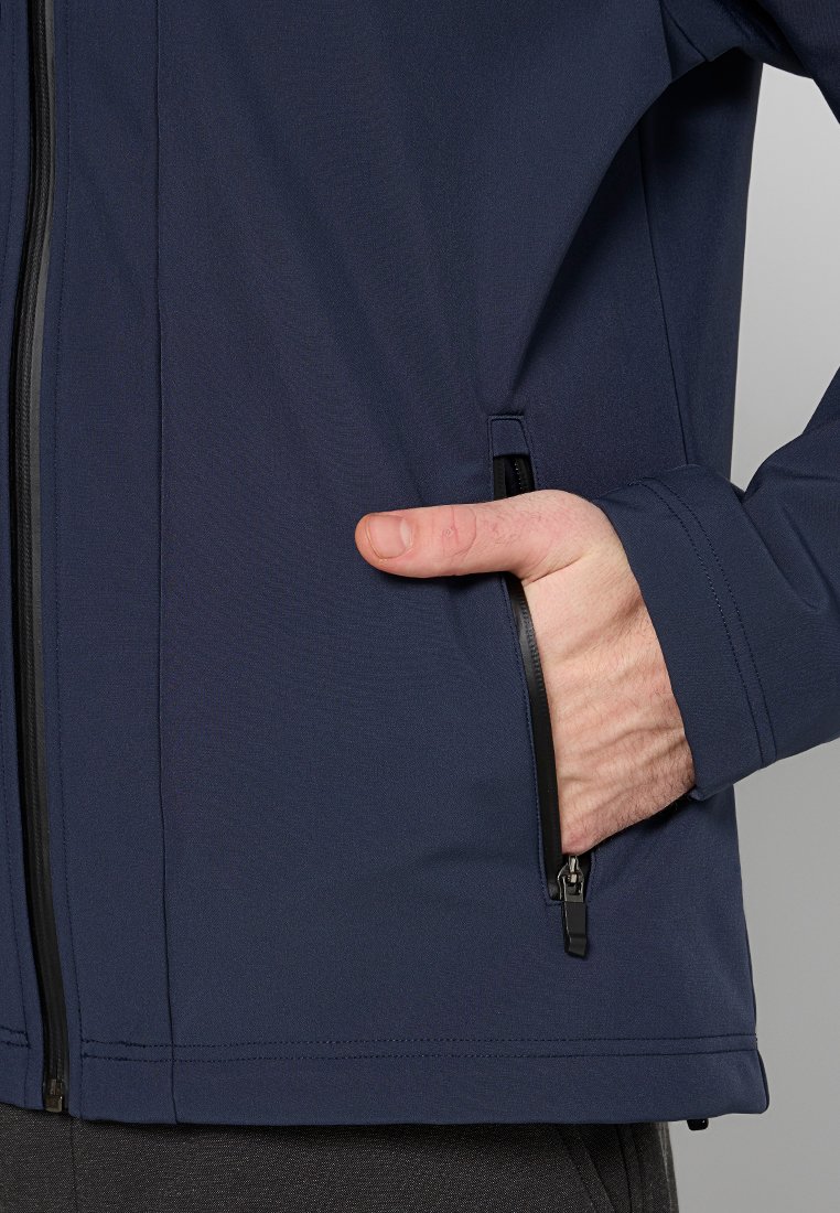 Marineblaue Softshelljacke mit einer Reißverschlusstasche, glatter Textur, taillierter Passform und verstellbaren Bündchen. Reißverschluss und Nähte in Schwarz.