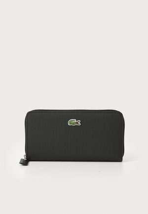 Cartera negra con cremallera hecha de tela texturizada, que presenta un logotipo de cocodrilo bordado en verde en la parte frontal. Diseño compacto y rectangular.