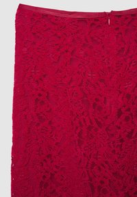 Roter Spitzenrock mit floralen Mustern, strukturierter Oberfläche und einem verdeckten Reißverschluss auf der Rückseite zum Schließen.