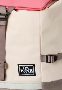 A rectangular backpack with a pink top and beige body, featuring brown straps and a DA KINE label. Made of durable fabric with smooth texture.