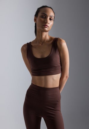 Top court brun et leggings taille haute assortis en tissu lisse et extensible, avec un décolleté arrondi et une silhouette ajustée.