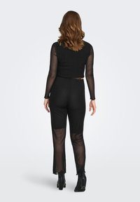 Must mustkombinees pikkade läbipaistvate võrgusvarrukatega ja täpilise mustriga. Vöökoht on liibuv, sääred sirged ning servas on küljelõhed. Mustad pahkluu saabid.