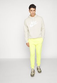 Nike Sportswear CLUB JGGR - Tracksuit bottoms - yellow strike