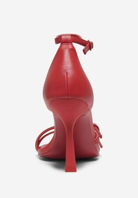 Sandalo con tacco alto in pelle rossa, punta affusolata, tacco a stiletto sottile, cinturino sottile alla caviglia e design minimalista.