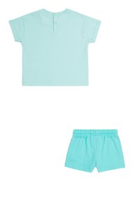 Camiseta corta de manga corta en color turquesa claro con botones en la espalda y pantalones cortos a juego con cintura elástica, ambos fabricados en algodón suave y transpirable.