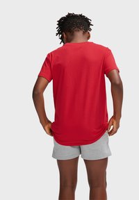 Rød bomulds t-shirt med korte ærmer, rund halsudskæring og en afslappet pasform, parret med grå shorts lavet af blødt stof.