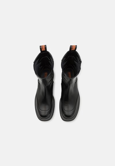 Botine negre din piele cu un finisaj neted, cu laturi elastice și un material texturat contrastant în interior. Au un tab de prins în spate.