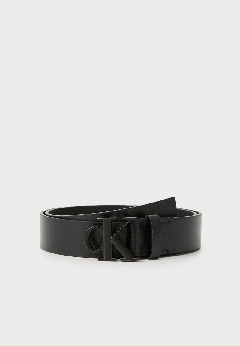 Ceinture en cuir noir avec une finition lisse, boucle ronde avec un logo 'CK' en relief, et longueur ajustable. Design simple et classique.