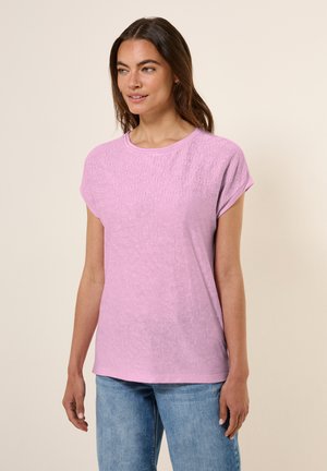 Light pink short-sleeve T-shirt with a round neckline and textured wave pattern at the front, paired with blue denim jeans.