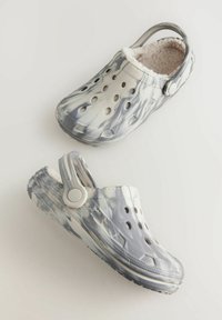 Sabots gris marbrés avec des trous de ventilation, doublure intérieure douce et une sangle arrière. Fabriqués en matériau flexible avec une semelle texturée.