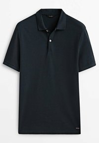 Polo en bleu marine foncé fabriqué en coton lisse. Dispose d'un col classique, d'une patte de boutonnage à deux boutons et de manches courtes. Étiquette de marque discrète à l'ourlet.