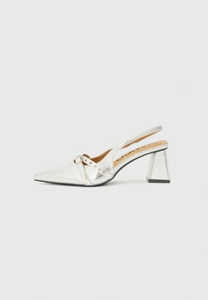 Silver slingback high heel with a pointed toe and textured surface, featuring decorative straps and a block heel design.