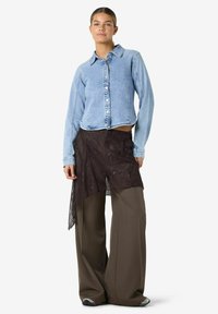 Denimist särk, hele sinine, nööbitav laia kraega. Must pitsiline asümmeetriline pealiskleit pruunide laiade pükste ja spordijalatsitega.