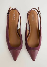 Burgundy slingback-korkoken, joissa on sileä nahkainen terävä kärki ja pehmeä kangasosa. Ominaisuuksiin kuuluu avoimet sivut ja soljella säädettävä nilkkahihna.