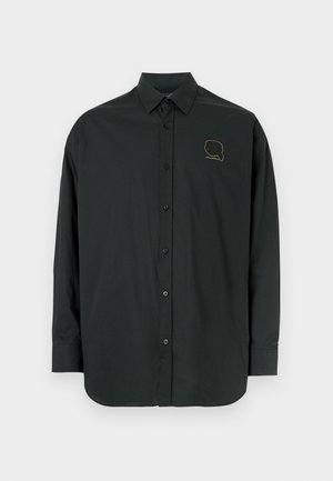 Crna košulja dugih rukava na kopčanje s glatkim tkanjem, s malim zlatnim logom na lijevoj strani prsa i klasičnim ovratnikom.