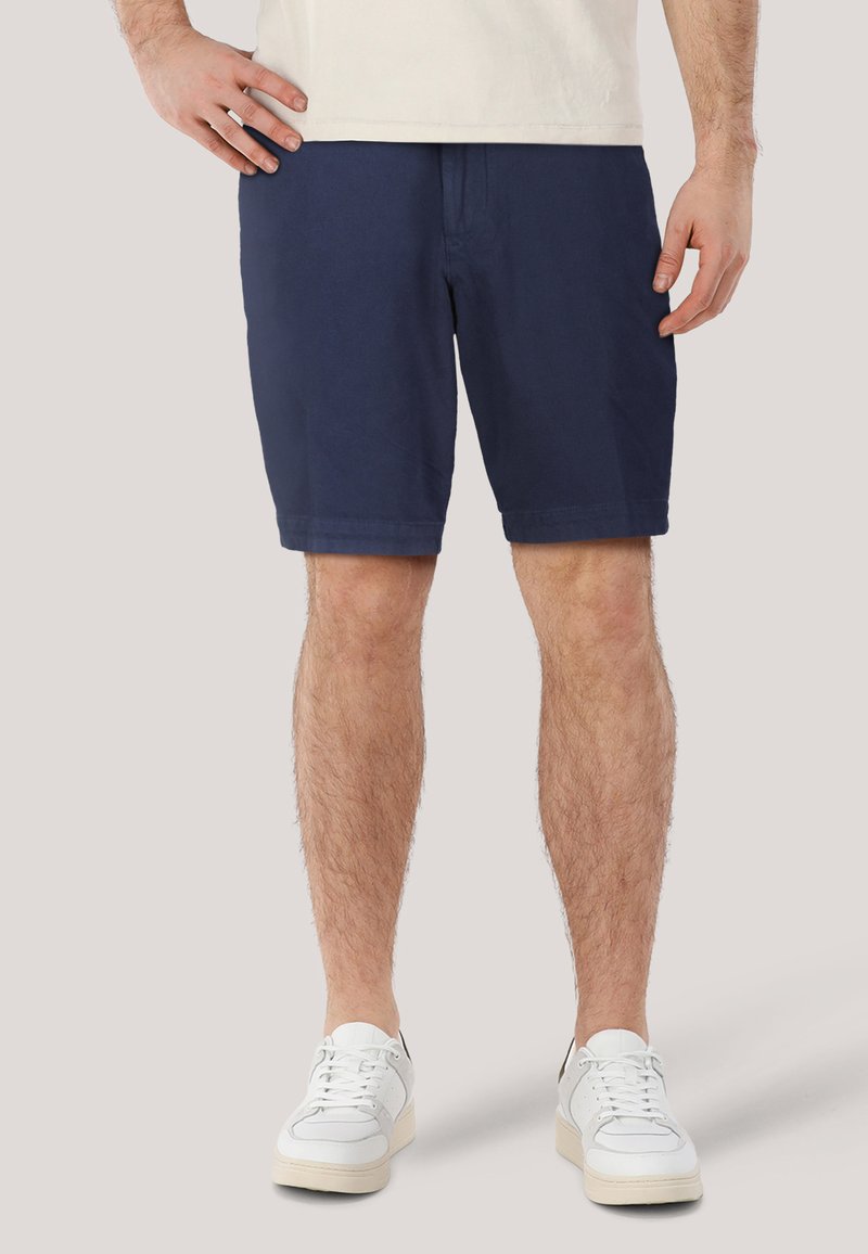 Marinblå bomullsshorts med rak passform, knälånga, med dragkedja och sidofickor, i kombination med vita sneakers.