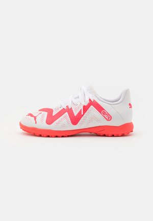 Scarpe da ginnastica bianche con accenti zigzag rosa, tomaia perforata, lacci bianchi e suola arancione brillante. Presenta un logo Puma di lato.