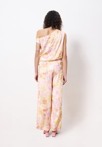 Blumiger Jumpsuit in zartem Pink, mit einem schulterfreien Design, weitem Hosenbein und einem weichen, leichten Stoff mit Blumenmustern.